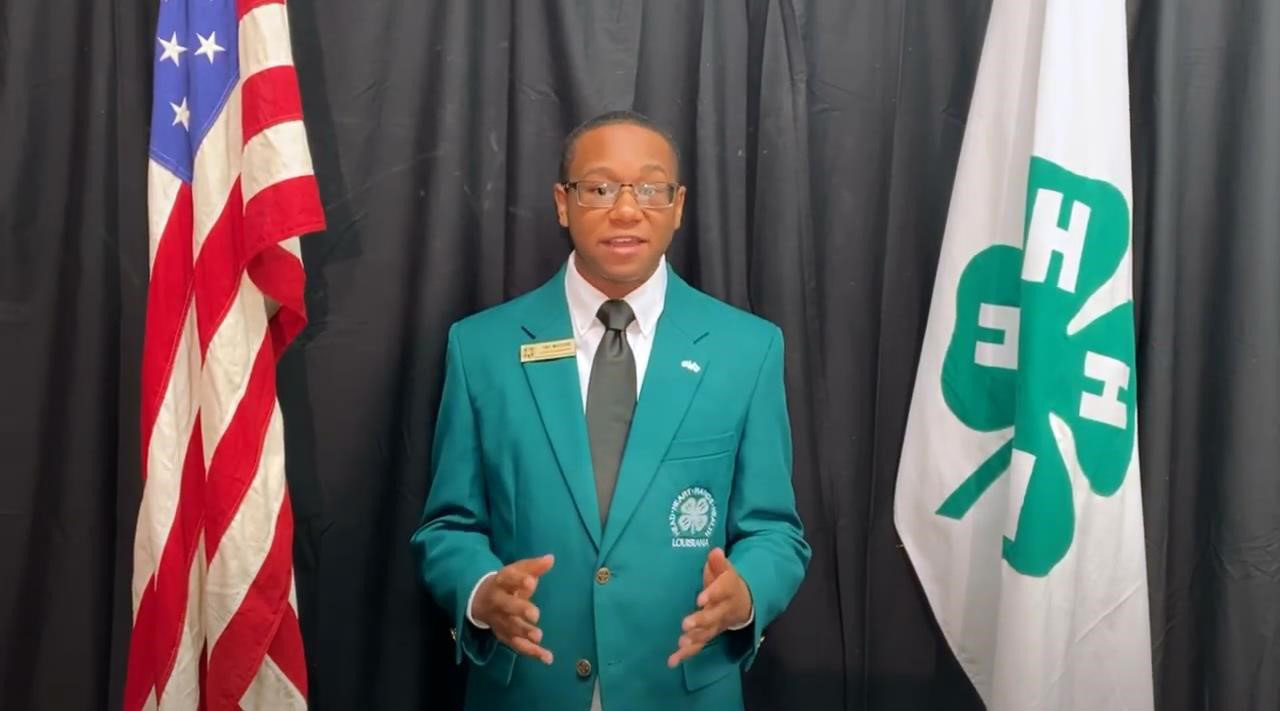 Young man in green jacket giving a speech.